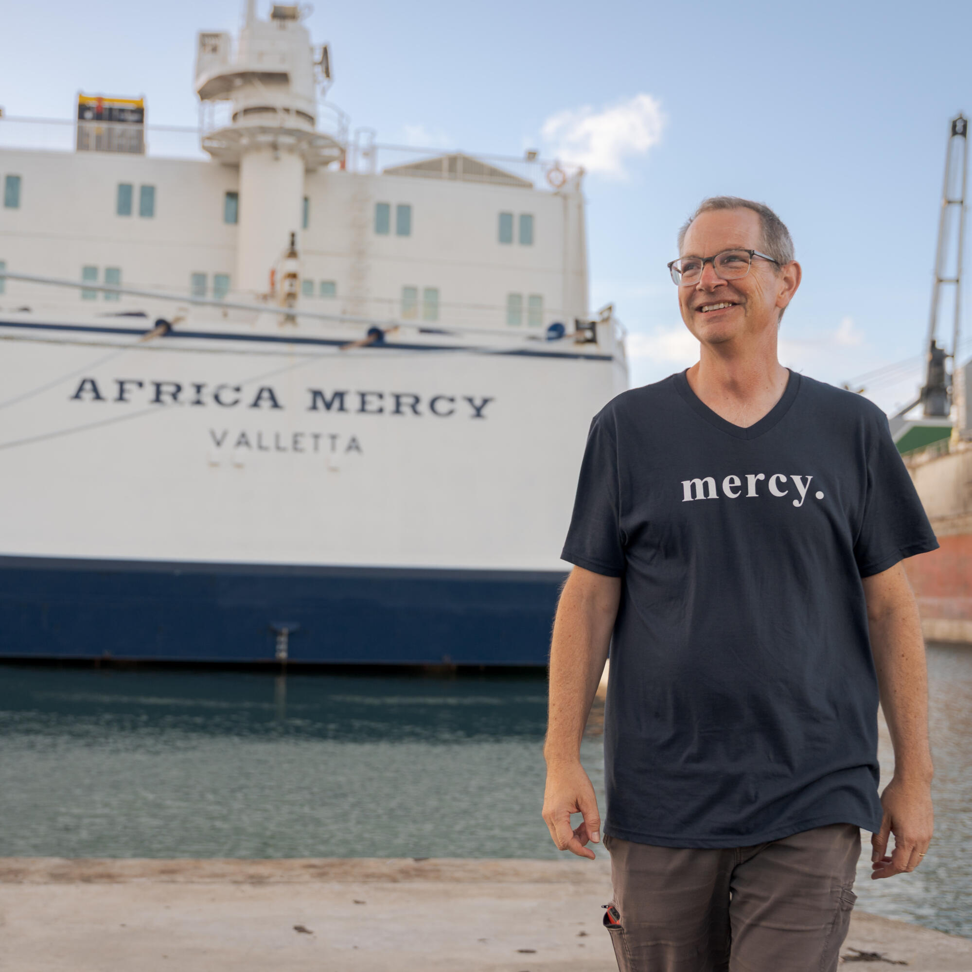 A Spoonful of Laughter John Branyan in front of the Africa Mercy for A Spoonful of Laughter Comedy Special